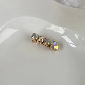 Close-up of gold hairpin featuring four round rhinestones in blue and aurora colors
