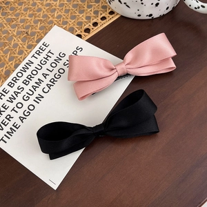 Detailansicht von rosa und schwarzen Satin-Schleifen-Haarspangen im Vintage-Stil auf Holz