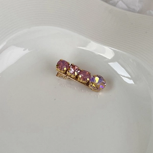Detailed view of pink and purple rhinestone hair clip on a white ceramic tray