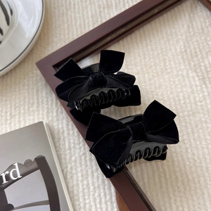 Elegant black velvet bow hair clips for women on a stylish minimalist background