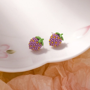 Detail view of purple berry earrings with green leaves on decorative porcelain plate