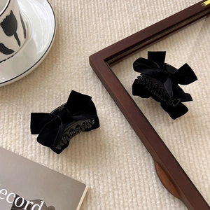 Close-up of elegant black velvet bow hair clips on a soft textured background