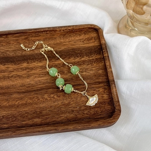Détail du bracelet feuille de ginkgo dorée avec perles vertes et incrustation nacre