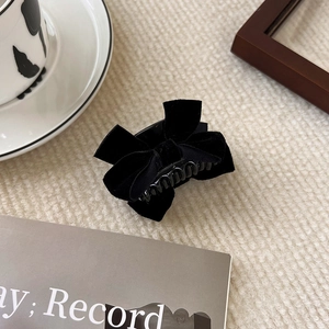 Close-up of a black velvet bow hair claw clip with elegant texture and soft indoor lighting