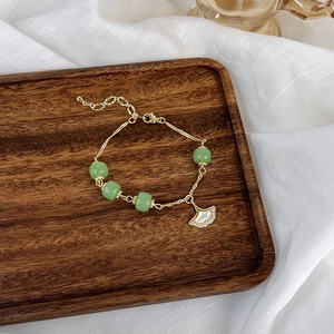 Détail du pendentif feuille de ginkgo sur chaîne dorée avec des perles vertes