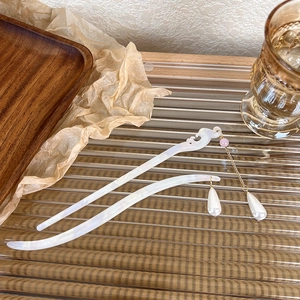 Detail of elegant acetate hair pins with pink beads and golden tassels on glass tray