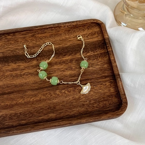 Bracelet feuille de ginkgo avec perles vertes et nacre sur plateau en noyer