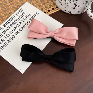 Schicke Haarspangen mit rosa und schwarzer Satinschleife auf rustikalem Holztisch