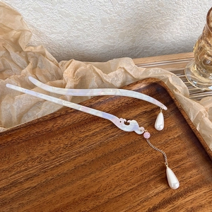 Detailed shot of acetate hair sticks with marble texture and delicate metal tassels