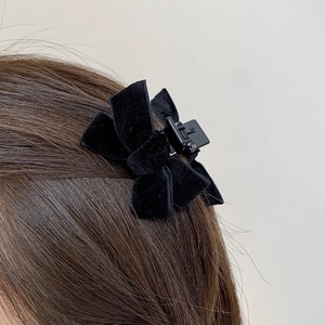 Elegant black velvet bow hair claw clip for women on brown hair, side view hairstyle accessory
