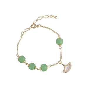 Bracelet feuille de ginkgo avec perles vertes et chaîne dorée sur fond blanc