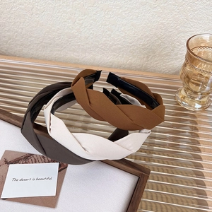 Close-up of three twisted fabric headbands in brown and beige on a glass tray