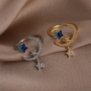 Elegant starry sky rings with moon and star zircon accents on a brown satin background