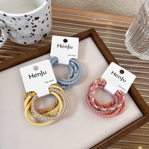 Close-up of colorful braided elastic hair bands in yellow, blue and pink on display card