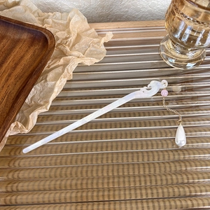 Detail of elegant Chinese style hair pin with white acetate carvings and pearl tassel