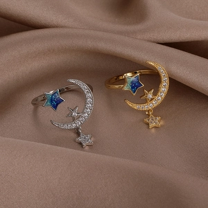 Detail view of gold and silver moon and star open rings on brown silk fabric
