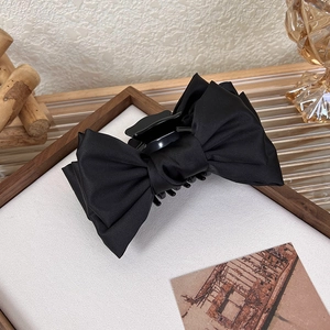 Close-up of black silk double bow hair claw clip with elegant ruffled texture detail