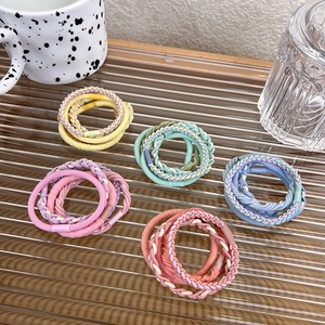 Close-up of candy-colored braided hair ties in various textures on a glass tray