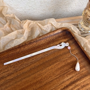 Macro view of Chinese style acetate hair pin with cloud carving and pearl tassel