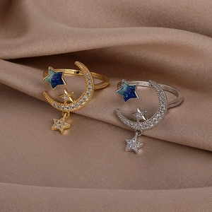 Detail of star and moon open rings with blue gradient glitter on champagne silk background
