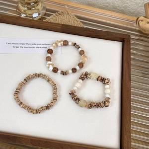 Detailed set of three beaded bracelets with wood beads, pearls and shell accents