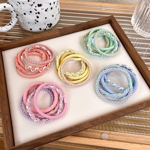 Detailed view of macaron colored braided hair ties set in a clean white wooden tray