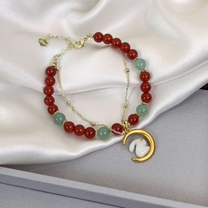Macro detail of a double-layer bracelet with red agate, moon pendant and white jade rabbit
