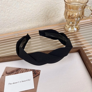 Detail view of black twisted fabric headband with non-slip inner teeth and chic texture