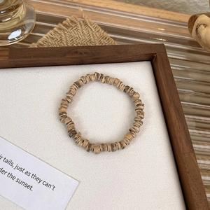 Detail of beaded bracelet with natural wood flakes and shell stones in vintage style