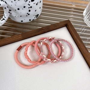 Detailed view of 5-piece pink elastic hair ties with braided and smooth textures