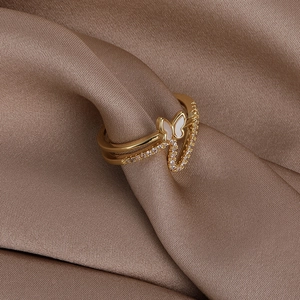Detail of a golden double-layered butterfly ring with shell wings and pavé zircon stones