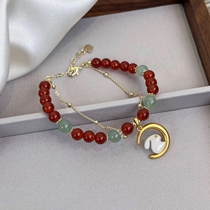 Detail of double-layer bracelet with red agate beads and golden rabbit moon pendant