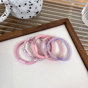 Detail of pink and purple braided elastic hair ties in a minimalist wooden tray display