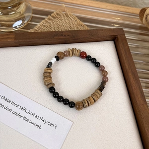 Macro shot of ethnic beaded bracelet with wood beads and black agate on white tray