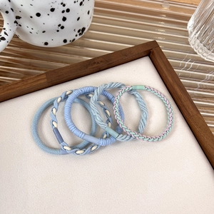 Set of 5 braided elastic hair ties in pastel blue and cream tones on wood display