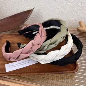 Detailed macro view of four braided satin headbands in green, pink, beige and black colors