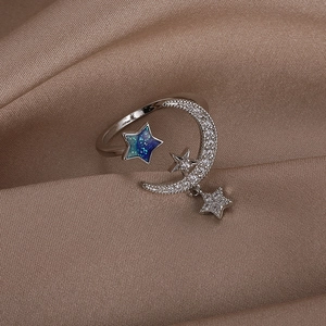 Detailed close-up of adjustable silver moon and star ring on elegant brown satin fabric
