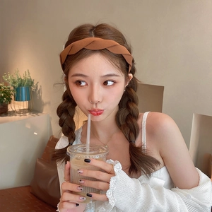 Stylish brown twisted fabric headband worn by model in a cozy cafe setting