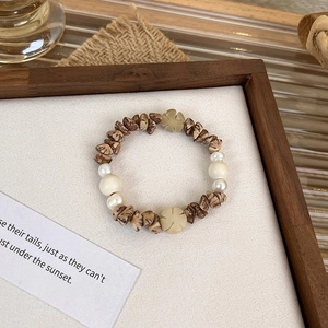 Detailed close-up of handmade wood bead bracelet with baroque pearls and flower charms