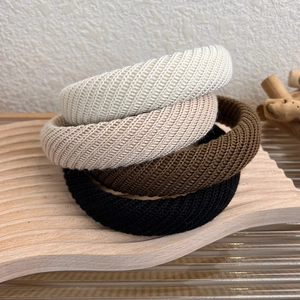 Dettaglio di quattro fasce per capelli in maglia spessa in colori autunnali su vassoio