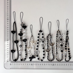 Detail view of 7 black and white beaded phone charms with scale ruler for size reference