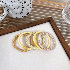 Detailed close-up of colorful high-elastic braided hair ties in a luxury wooden tray