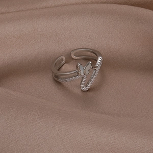Detailed close-up of shell butterfly ring with zircons on champagne silk fabric