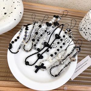 Minimalist black and white beaded phone strap with heart and pearl charms in a dish