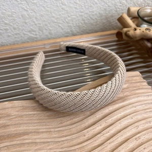 Dettaglio fascia in maglia beige con etichetta fatta a mano su espositore in legno