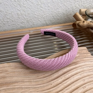 Vista dettagliata della fascia in maglia rosa con etichetta fatta a mano e trama a coste