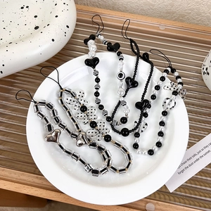 Detail of five black and white beaded phone straps with hearts and bows in a ceramic dish