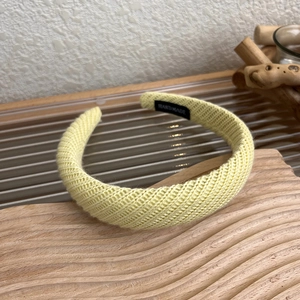 Dettaglio della fascia in maglia giallo chiaro con etichetta fatta a mano su base in legno