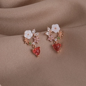Macro detail of rose gold flower earrings with colorful zircon and red heart gemstone