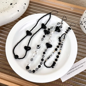 Close-up of three black and white beaded phone straps with heart and pearl details
